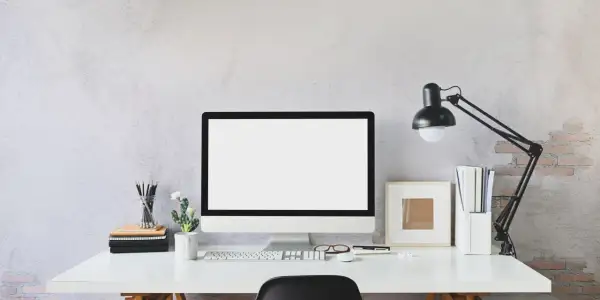Nowoczesne biurko z monitorem, klawiaturą i lampką. Idealne miejsce do pracy zdalnej, gdzie pulpit zdalny pozwoli Ci połączyć się z biurem.