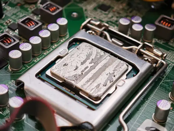 Procesor z zaschniętą pastą termoprzewodzącą, gotowy do testu chłodzenia CPU. Widoczne kondensatory i elementy płyty głównej.