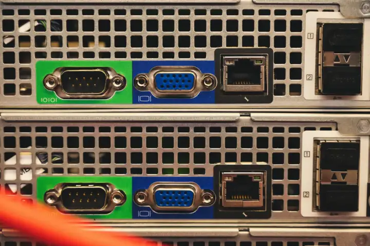 Zbliżenie na tylny panel dwóch serwerów, widoczne porty VGA, RJ45 i SFP. Trwa budowa serwera.